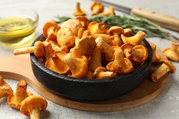 Chanterelle mushrooms, knife, oil and rosemary on grey table, closeup © New Africa