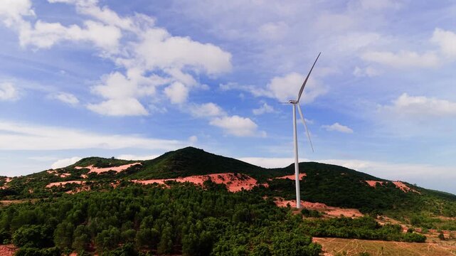 In Hoa Thang, Lam Dong, wind turbines rotate over green hills. The sun shines bright as clouds move across the sky. Nature blends with technology in this lively area.