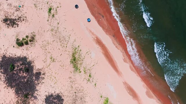 People enjoy their time at Hoa Thang, Lam Dong. They walk on the sandy beach with some umbrellas nearby. The waves crash softly on the shore under a bright sky.