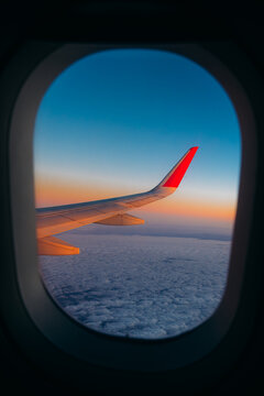 Clear blue sky and soft white clouds outside an airplane window during daytime flight