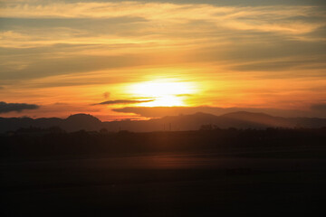 Fototapeta premium Golden sun setting behind layered mountain silhouettes over Bogota