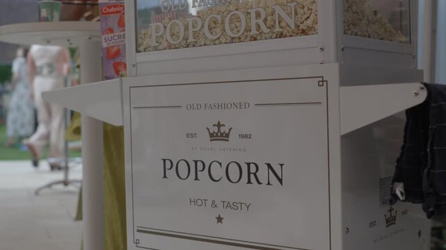 Old fashioned popcorn machine filled with fresh popcorn stands at an indoor wedding reception