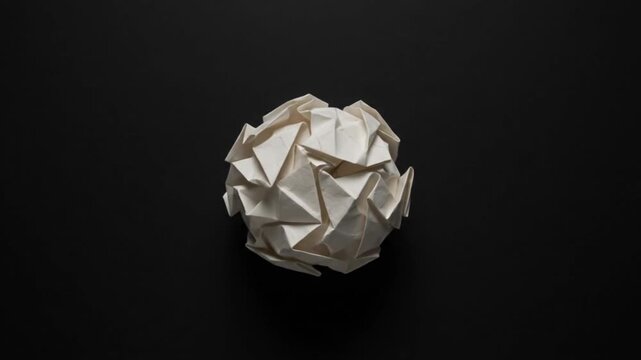 Origami Paper Folding Into Abstract Geometric Ball on Black Background