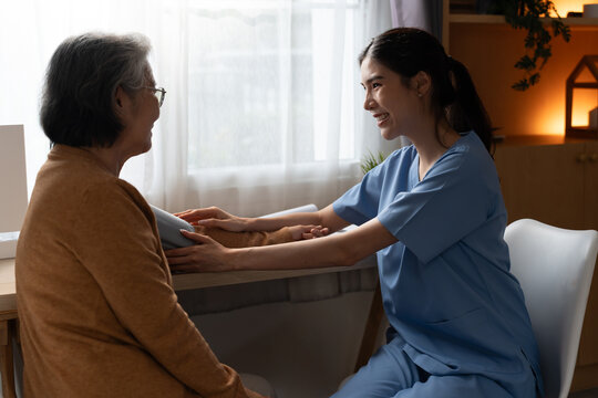 Smiling female nurse caring for a senior woman during a blood pressure check at home, representing compassionate nursing, preventive healthcare, trust, wellness and healthy aging support.