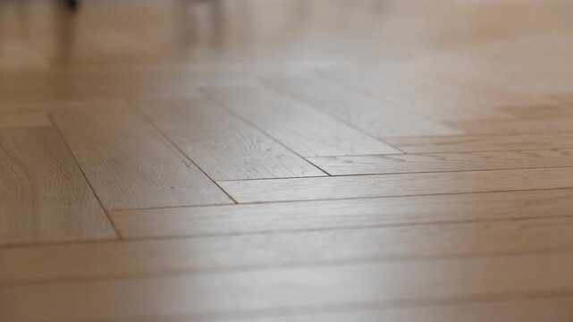 Camera glides left across warm herringbone parquet with a shallow focus