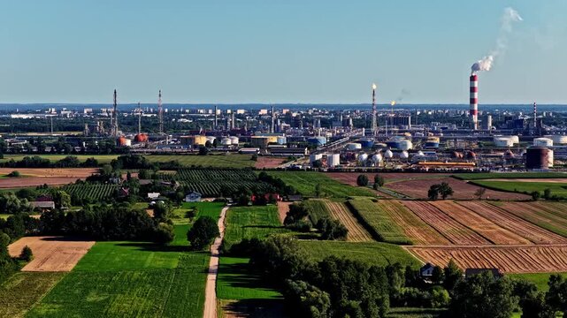 Aerial view of Orlen Plock Production Plant with industrial chimneys, storage tanks, and surrounding agricultural fields in Plock, Mazowieckie, Poland.