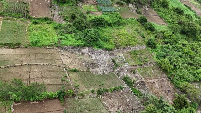 Drone flies from left to right along cultivated fields and terraced farmland on a steep mountainside in Zunil, Quetzaltenango, Guatemala.