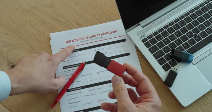Person holding a USB flash drive while completing a device approval request form, representing cybersecurity, data protection and secure workplace access.