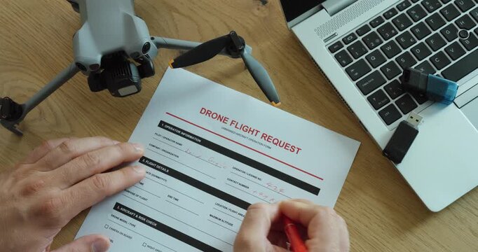 Person completing a drone flight request form beside a drone and laptop, representing flight authorization, aviation safety, regulations and professional drone operations.