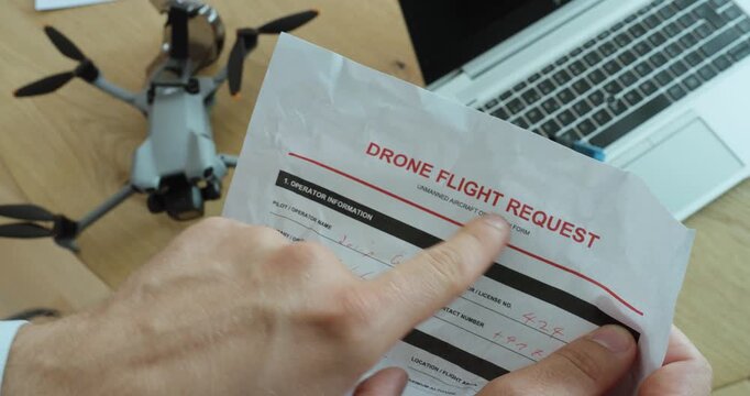Person reviewing a drone flight request document beside a drone and laptop, representing flight permission, authorization, aviation regulations and safe drone operation.