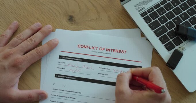 Person completing a conflict of interest declaration form at an office desk, representing business ethics, corporate compliance, transparency and professional disclosure.