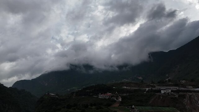 Drone flies forward toward dramatic mountains covered by dense low clouds and mist in Zunil, Quetzaltenango, Guatemala. Moody tropical highland scenery.