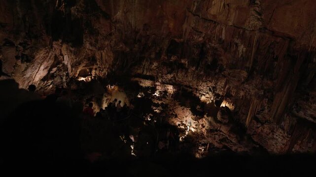 Tourists exploring a large illuminated cave