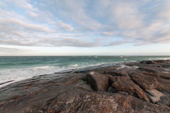 Indian Ocean waves washing over dark stone formations on a remote Australian beach