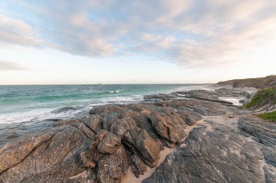 Wide coastal landscape with textured rocks and open sky providing natural copy space