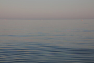 Obraz premium Minimalist peaceful calm sea horizon with gentle ripples at sunrise