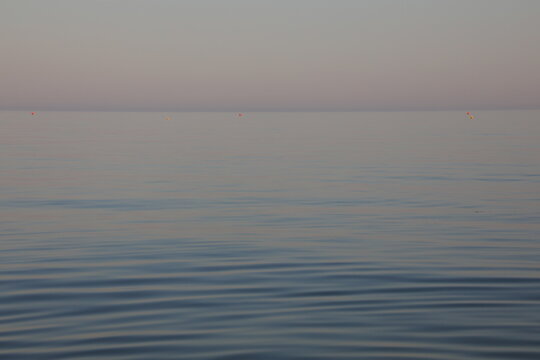 Minimalist peaceful calm sea horizon with gentle ripples at sunrise