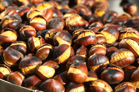 Freshly roasted chestnuts with cracked shells displayed on a street food stall