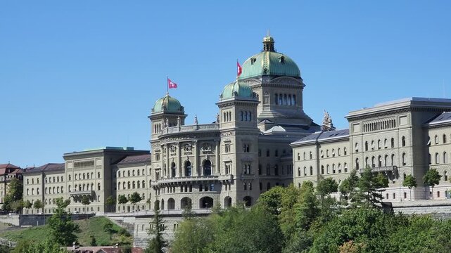 Panoramic view of the swiss parliament house or bundehaus in Bern on a sunny summer morning with flags waving.
