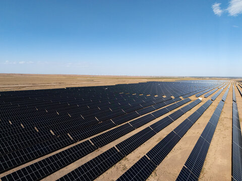 rows of solar panels in vast desert landscape under blue sky