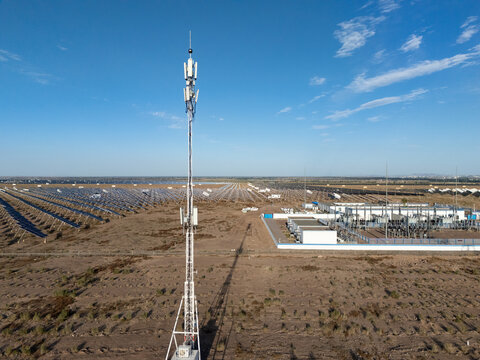 telecommunication tower standing in desert near solar power station