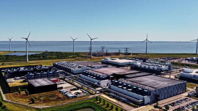 Aerial view of the Google Data Center facility featuring large industrial buildings and wind turbines along the coast in Eemshaven, Groningen, Netherlands.