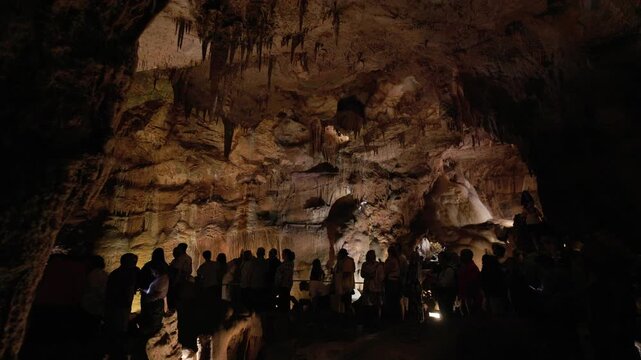 Group of tourists visiting a spectacular cave with stalactites