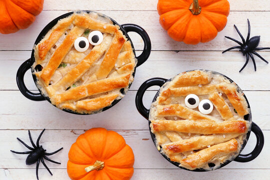 Halloween mummy chicken pot pies. Above view table scene on a white wood background.
