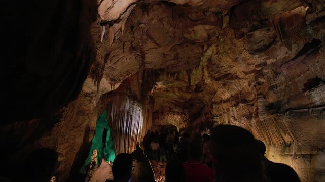 Tourists exploring illuminated stalactite cave formations
