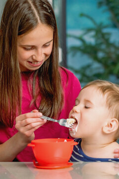 Sweet sibling moment as older sister feeds her baby brother.