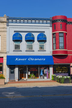 Small-town storefront featuring Xaver Cleaners with a bright blue awning, three dome windows Editorial Use only Plymouth, IN USA Aug 21, 2026. Neighboring red brick turret, capturing everyday urban ch