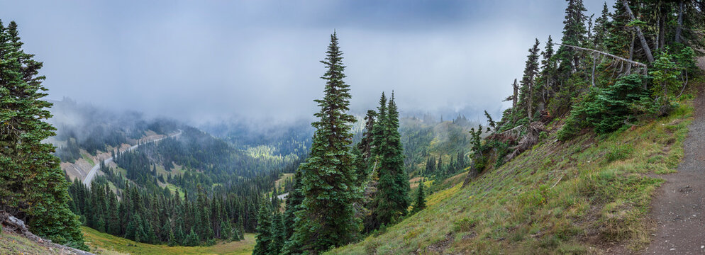Beautiful wide panoramic view of a mountain valley with a winding road and thick clouds