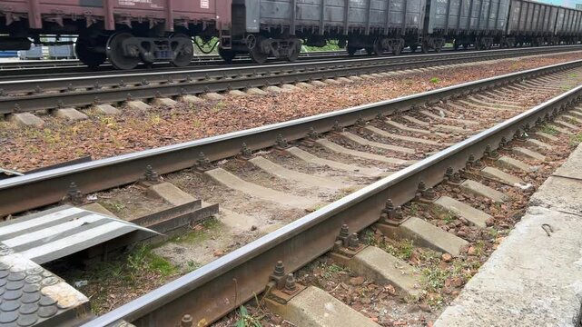 Moving freight train passes beside parallel steel railway tracks outdoors