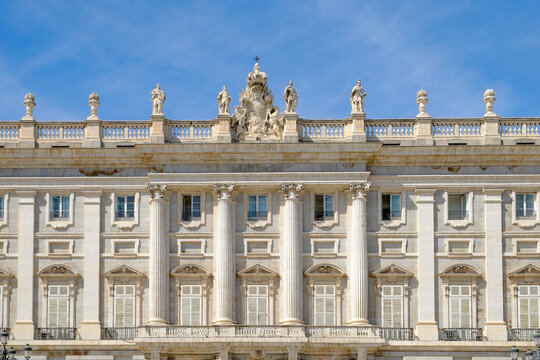 Grand palace facade with rooftop statues against blue sky