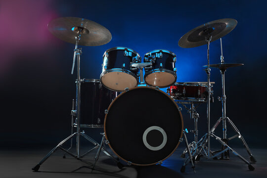 Drum set on dark background with blue light and smoke. Musical instrument