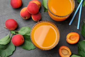 Apricot juice in glasses, fresh fruits and drinking straws on black table, flat lay © New Africa