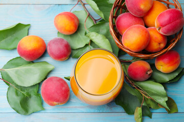 Apricot juice in glass, fresh fruits and leaves on light blue wooden table, above view © New Africa