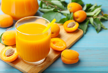 Apricot juice in glass and fresh fruits on light blue wooden table, closeup © New Africa