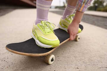 Woman riding skateboard on city street, closeup © New Africa