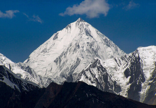 View of the snow-capped Rakaposhi peak rising against a clear blue sky in the rugged mountain landscape of Nagar, Pakistan.