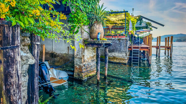 Traditional Italian lakeside atmosphere with a motorboat stored in a waterside boathouse garage, capturing the charm of lakefront living and boating on the Italian Lakes district