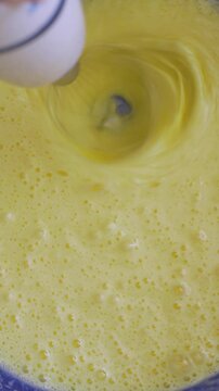 Home kitchen filled with scent of batter. Hand mixer whirls egg liquid dough in blue bowl. Whisk helps achieve perfect pancake consistency