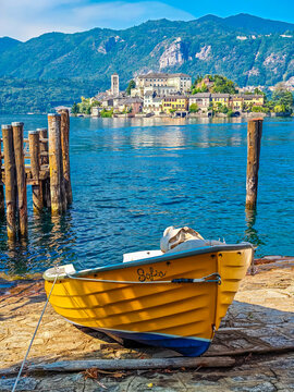 Traditional Italian atmosphere on Lake Orta, with a boat resting along the lakeshore and picturesque San Giulio Island in the background, Piedmont, Italy