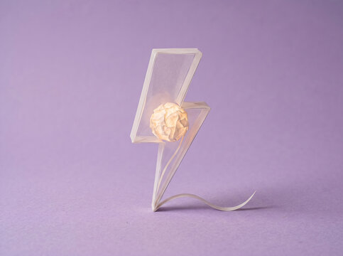 Miniature paper craft lightning bolt glowing with a crumpled paper ball inside, sudden burst of inspiration, creative spark, energy and innovation concept