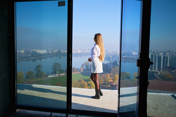 Naklejka premium Real estate manager presents high rise apartment with floor to ceiling windows and open balcony. Concept of home sales, urban development, investment and editorial use