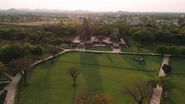 Aerial view of khajuraho hindu temple in madhya pradesh, india, with lush gardens and long shadows at sunset