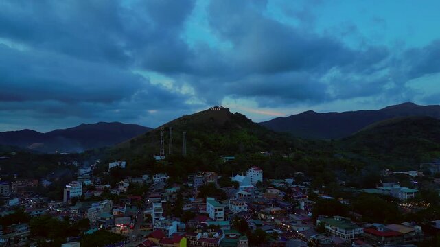 Illuminating Coron sign on Mount Tapyas with the town below, showcasing Palawan's popular travel destination at evening. Spectacular aerial view ascending raise up drone panorama