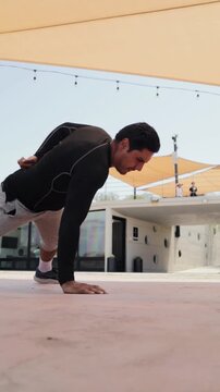 Determined athletic man performing a one-arm handstand push-up outdoors, showcasing his strength, balance, and calisthenics skills under a sunny sky