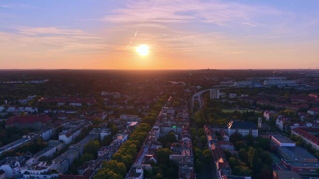 Berlin suburbs bathed in golden sunlight during 90 percent Solar Eclipse sunset, highlighting urban development and green spaces. Spectacular aerial view