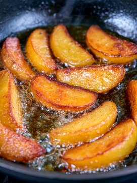 Golden potato wedges frying in hot oil skillet